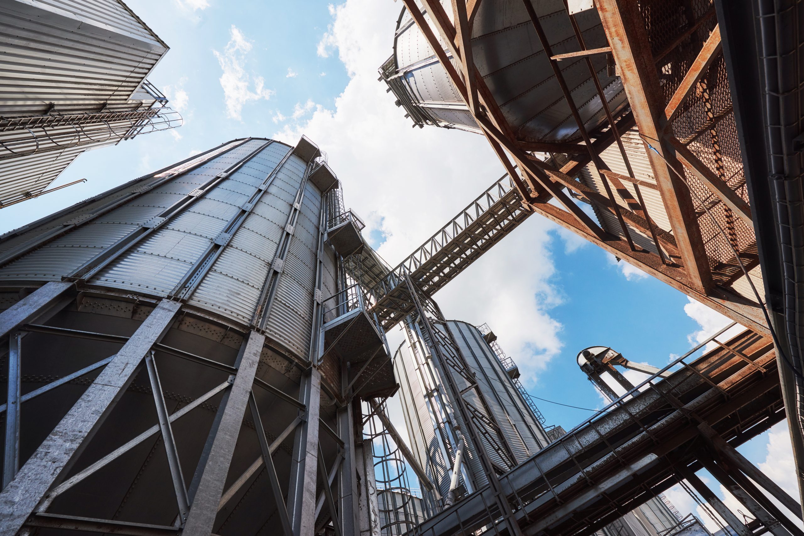 Agricultural Silos. Building Exterior. Storage and drying of grains, wheat, corn, soy, sunflower against the blue sky with white clouds